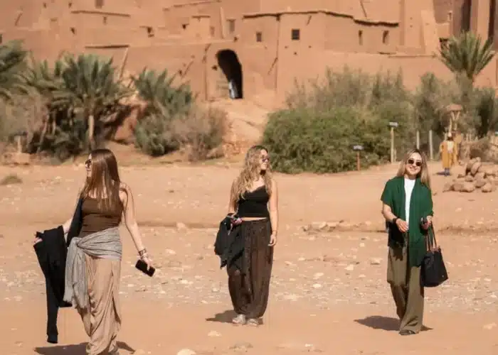 Viaggiatori nel deserto di Merzouga al tramonto durante il tour da Marrakech a Fes 6 giorni, con cammelli e dune dorate sullo sfondo.