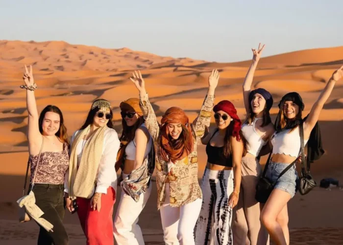 Veduta panoramica del deserto di Merzouga al tramonto durante un tour Marocco 6 giorni con Tour Deserto Marocco, con cammelli e dune dorate.